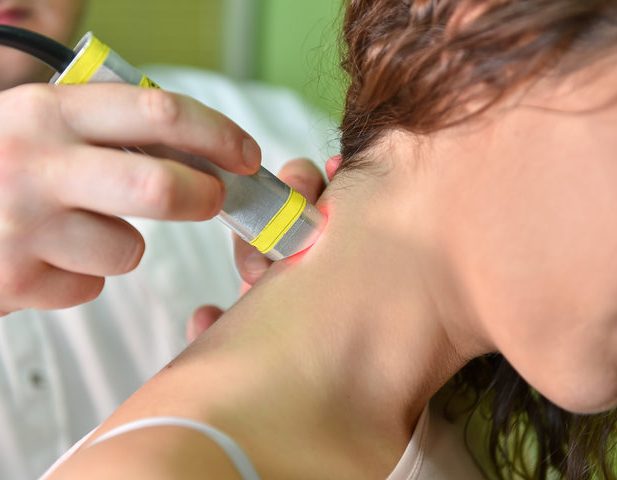 A person receiving treatment on their neck with a handheld device.