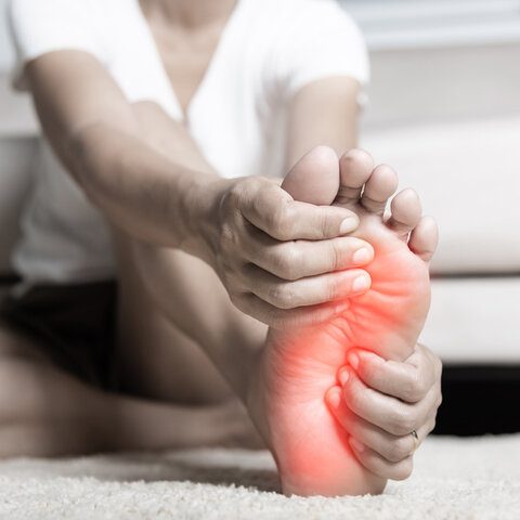 Foot pain A person stretching their foot, showing signs of discomfort or pain.
