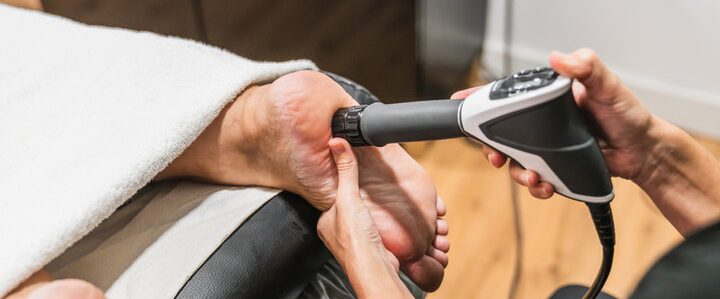 A person receiving treatment on their foot with a handheld device.