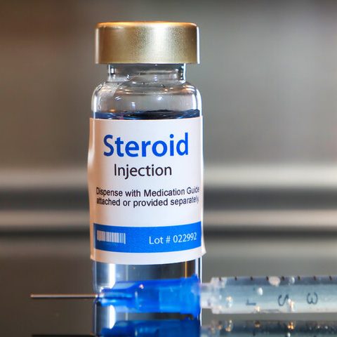 Container of steroid injection with a syringe beside it.