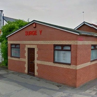 Brick building with "Surge Y" signage, featuring windows and a brown door.