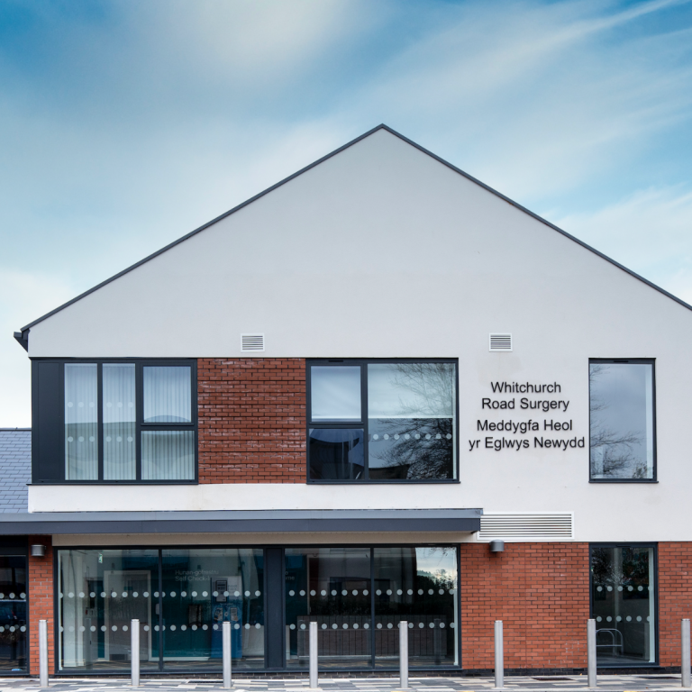 Modern building with a mix of white and brown facades, featuring large windows and signage.