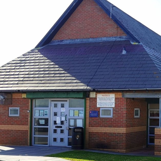 A brick building with a sloped roof and landscaped greenery.